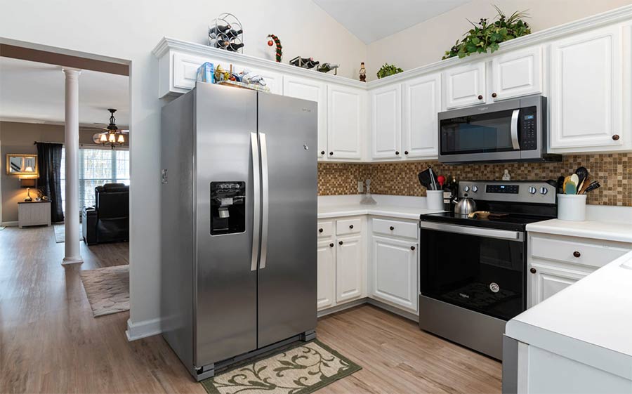 Modern kitchen with stainless steel appliances, white cabinets, and a tiled backsplash.