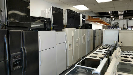 2025-10-03 Rows of refrigerators, stoves, and microwaves displayed in an appliance store showroom.