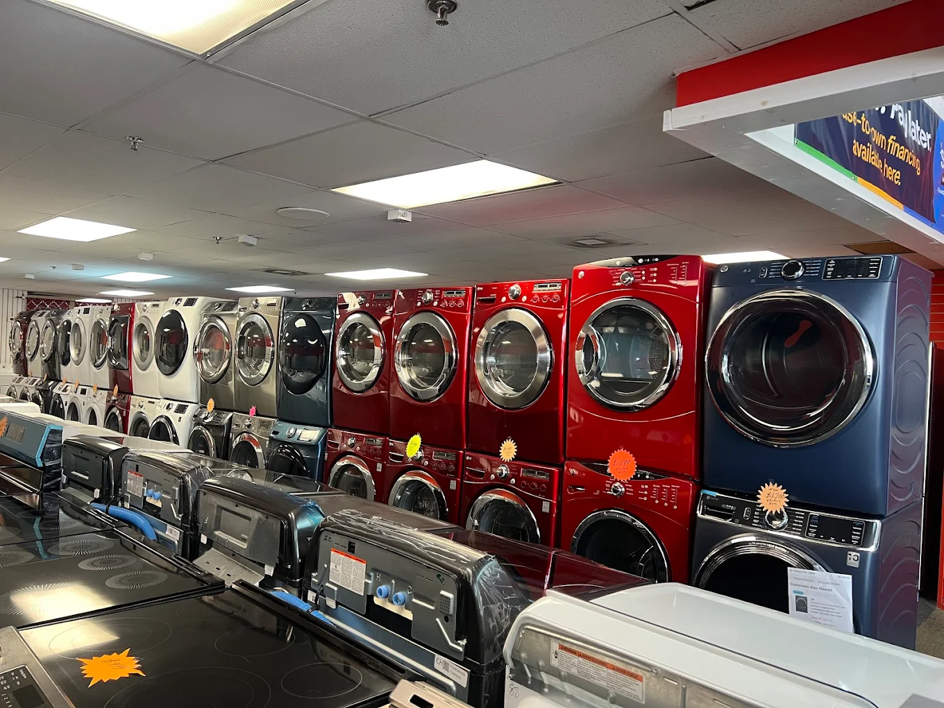 unnamed Rows of colorful washers and dryers on display in an appliance store showroom.